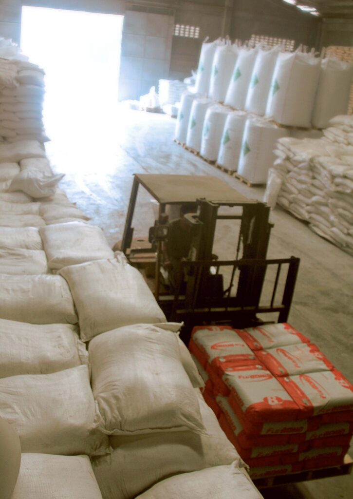 a forklift carrying a sack of raw materials in a warehouse full of sacks of raw materials